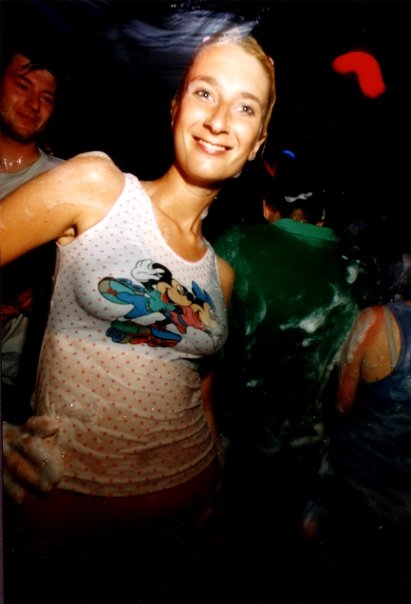 A clubber in a tank top, soaked by the foam, on the dance floor.