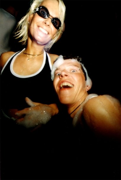 Two laughing clubbers wearing swimming goggles in the middle of the foam.