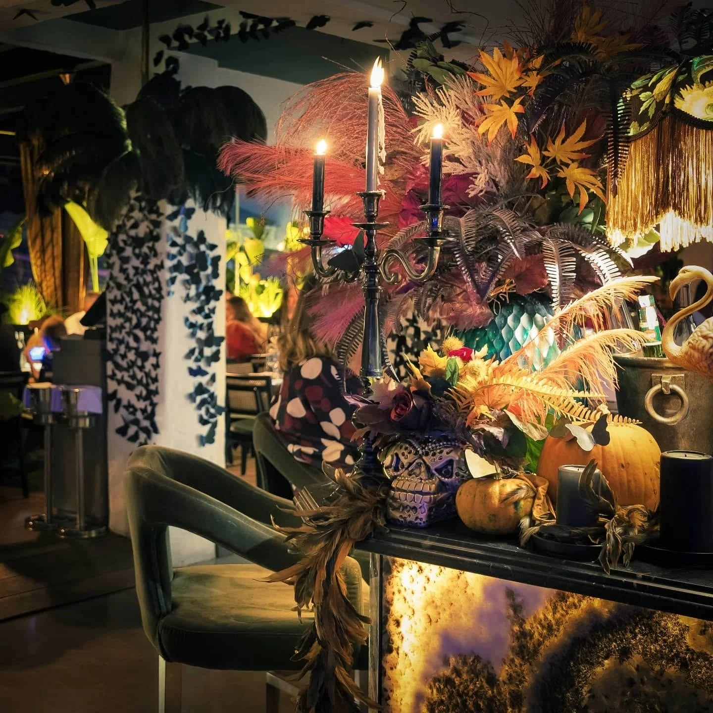 Pour une soirée de saison, la maison se costume : plumes noires et roses, chandeliers, papillons découpés, crâne peint et citrouilles. La manière d'Aldo Gigli reste la même depuis le Mirano : transformer la salle pour une seule nuit.