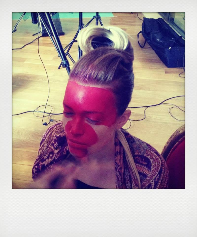 Application du maquillage rouge sur le visage du modèle.