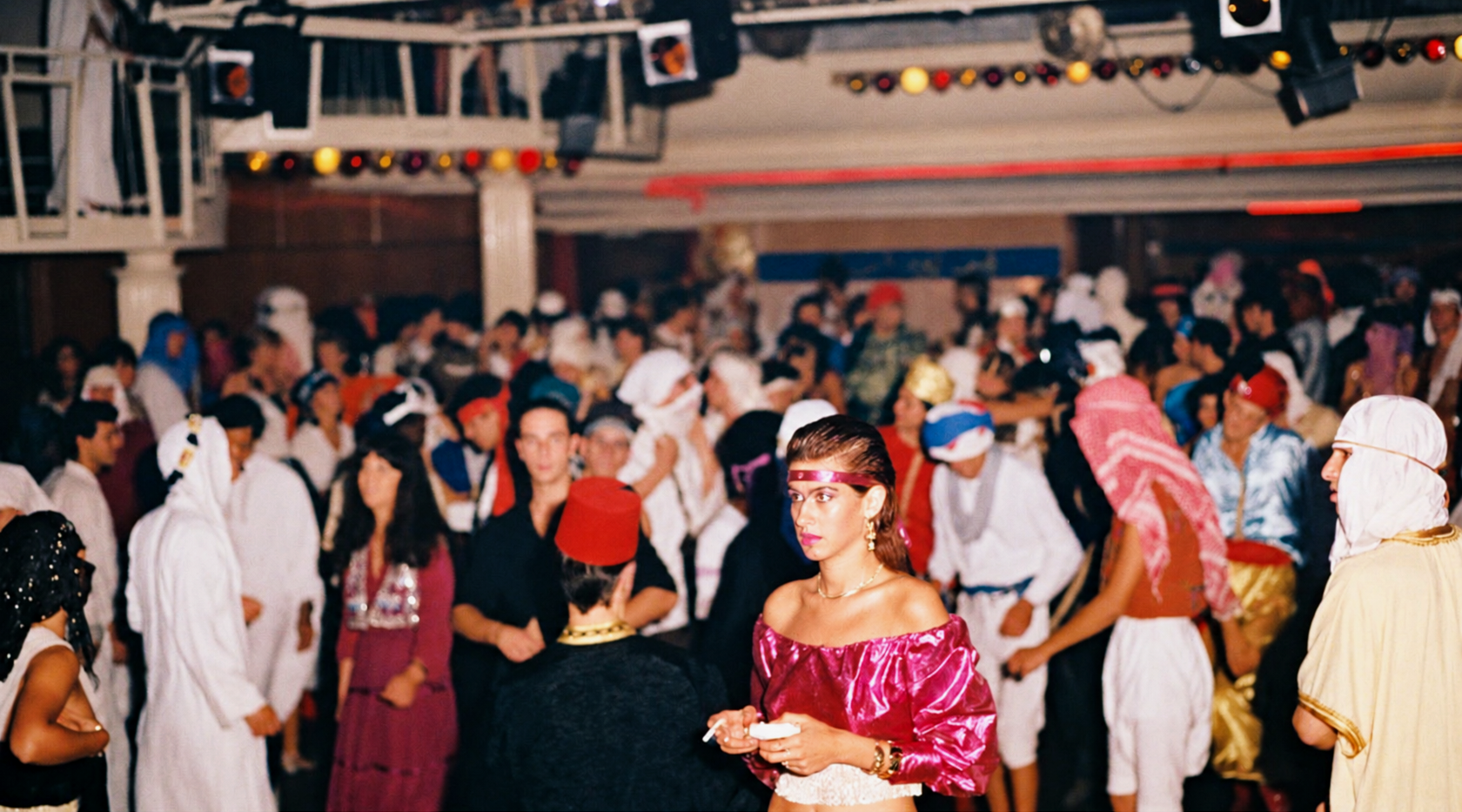 Photographie couleur, format horizontal. Invités en tenues orientales et fantaisistes dans la salle du Mirano Continental, entre turbans, caftans et maquillage de scène.