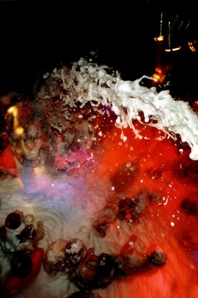 A wave of foam thrown over the dance floor, in the club's red lighting.