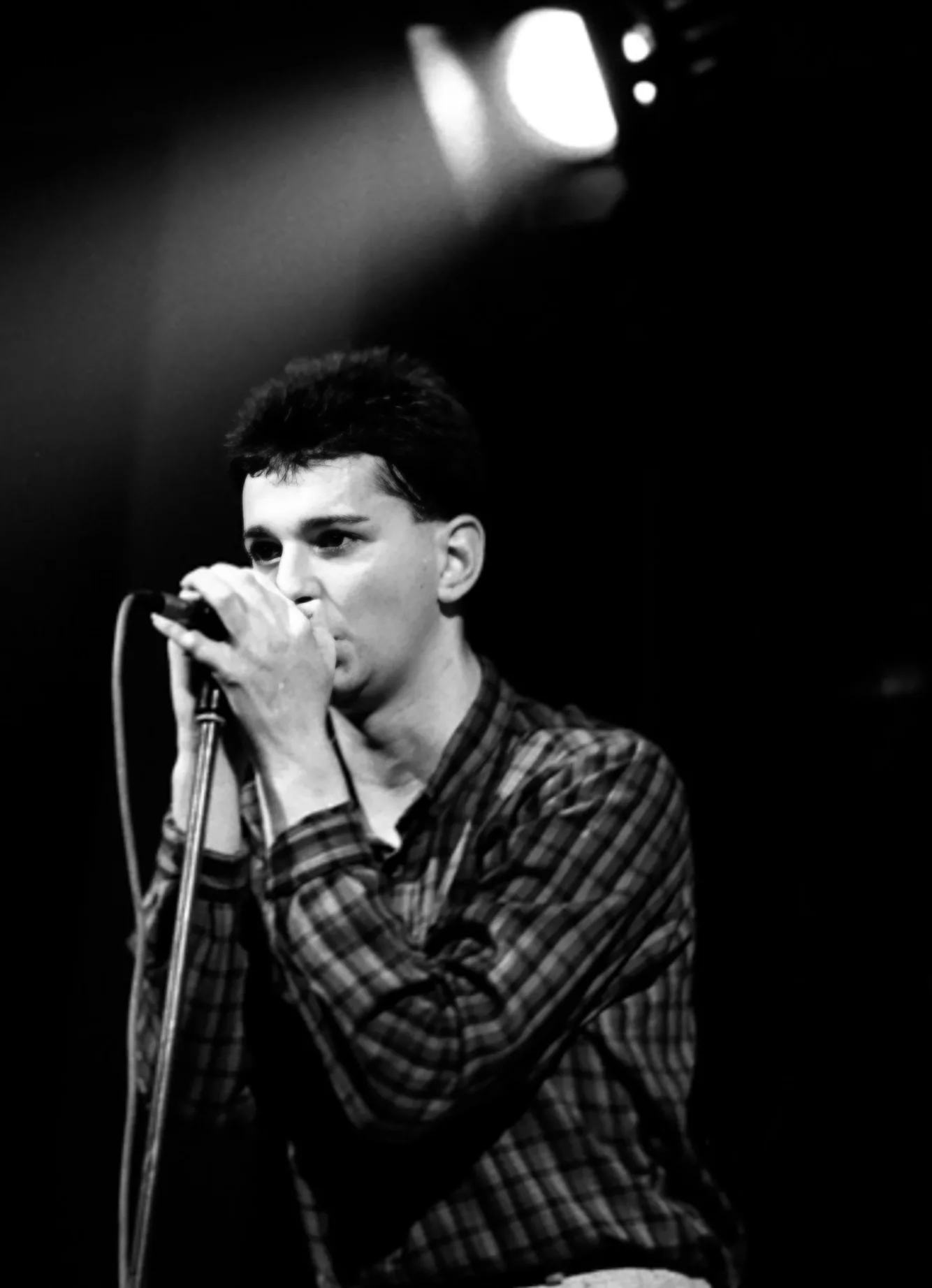 Dave Gahan dans le faisceau des projecteurs, micro en main, pendant le concert de Depeche Mode au Mirano, dimanche 12 décembre 1982. Photo © Philippe Carly.