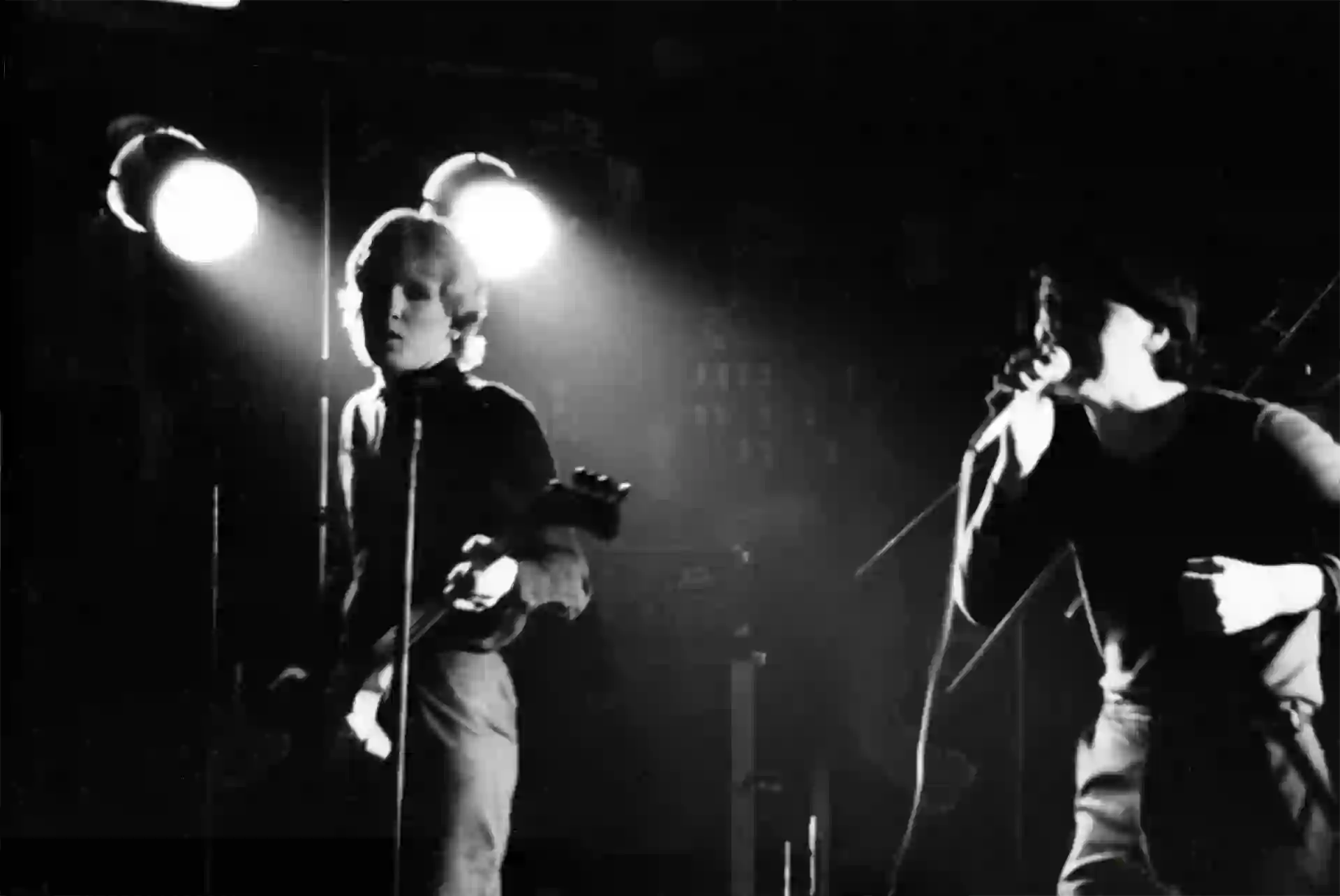 Derek Forbes et Jim Kerr sous les deux projecteurs jumeaux de la scène. Dernière image de la série : Simple Minds au Canotier, 18 octobre 1979.