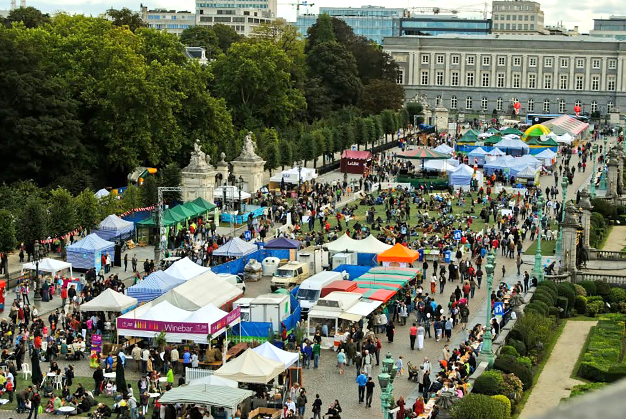 Vue plongeante sur le village de stands : marché bio, bar à vins, producteurs et animations, le long du parc de Bruxelles.