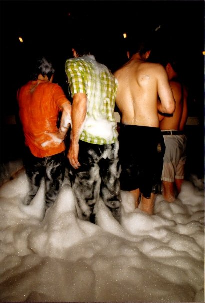 Four clubbers seen from behind, knee-deep in the foam.