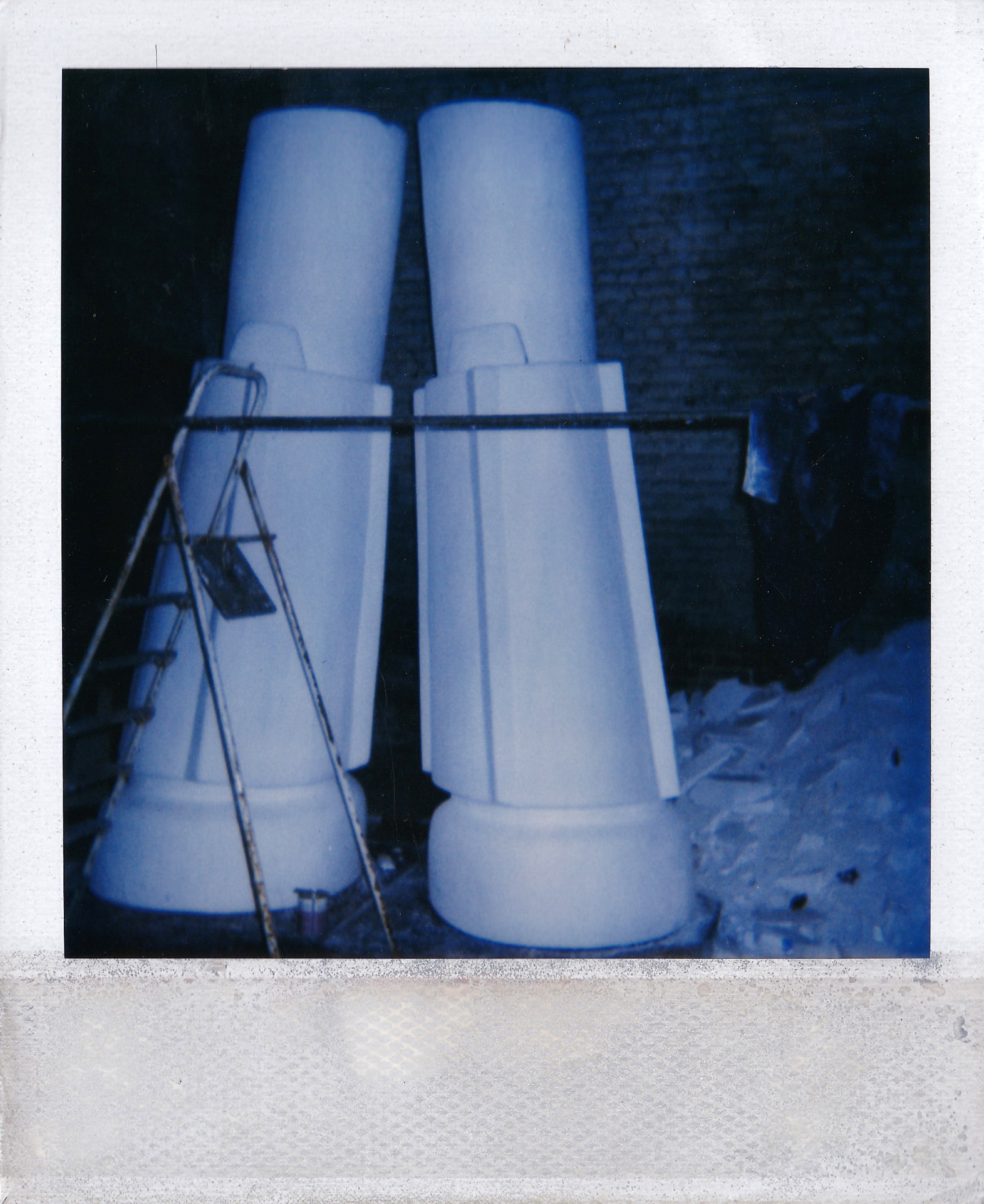 The two legs being finished in the workshop, propped against the brick wall.