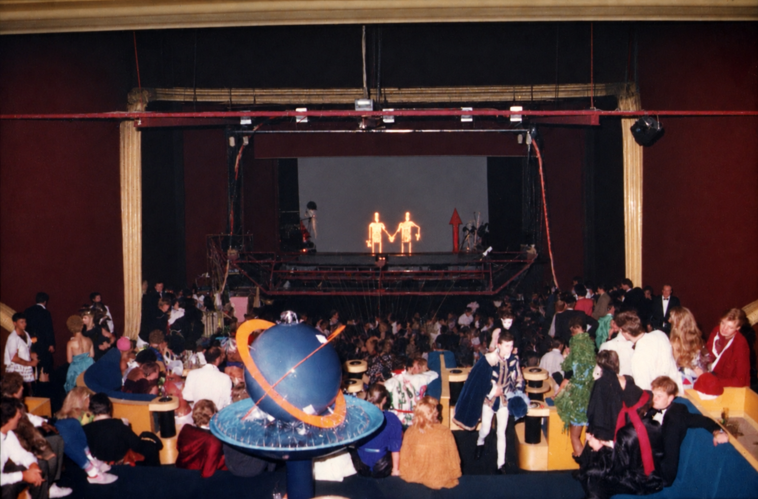 Photographie couleur, format horizontal. La piste du Mirano Continental sous un décor spatial : une sphère géante et des silhouettes costumées animent la scène, le public entourant le spectacle.