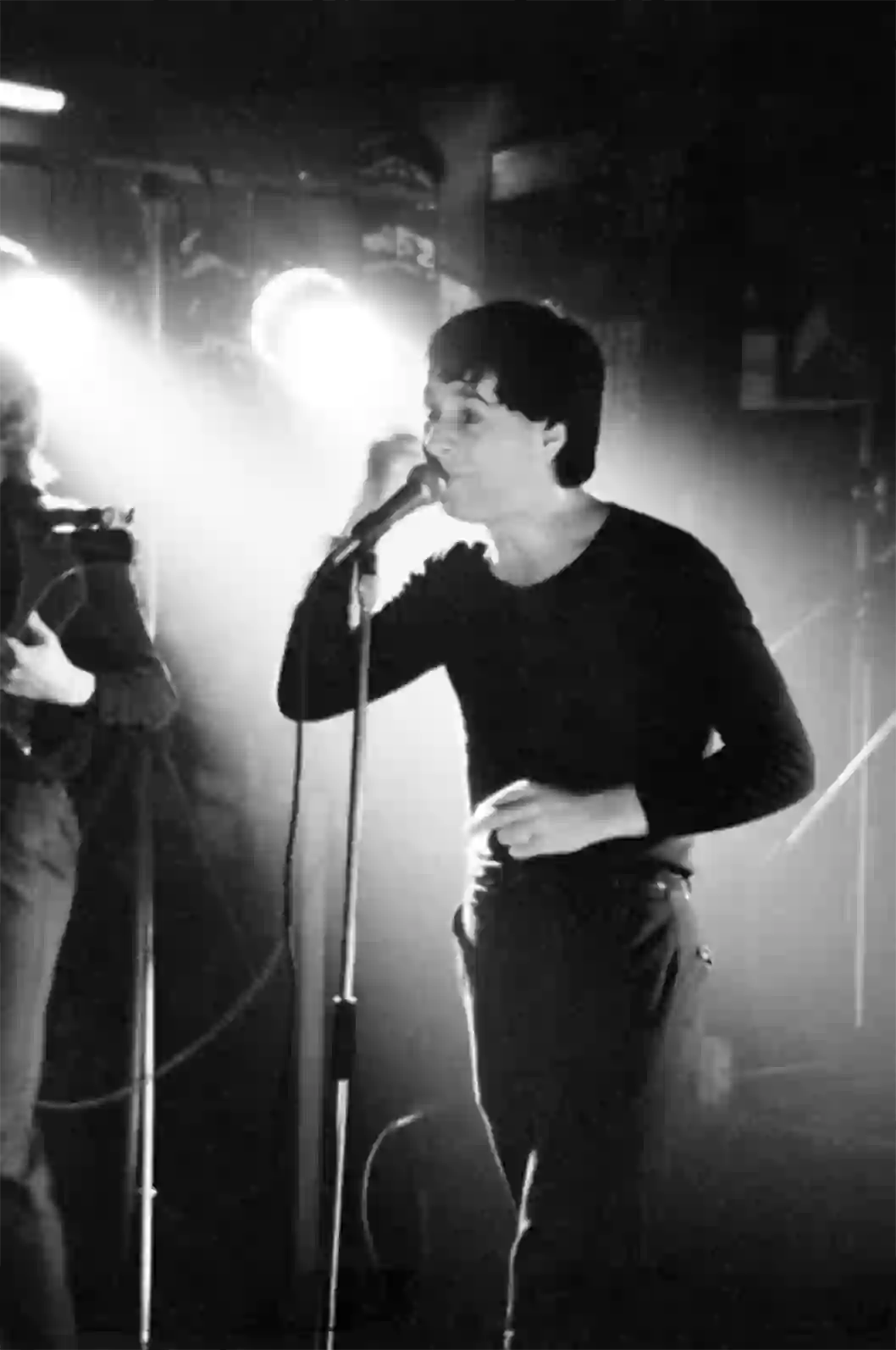 Jim Kerr au micro, éclairé par la rampe de projecteurs. Simple Minds, Le Canotier, 18 octobre 1979.