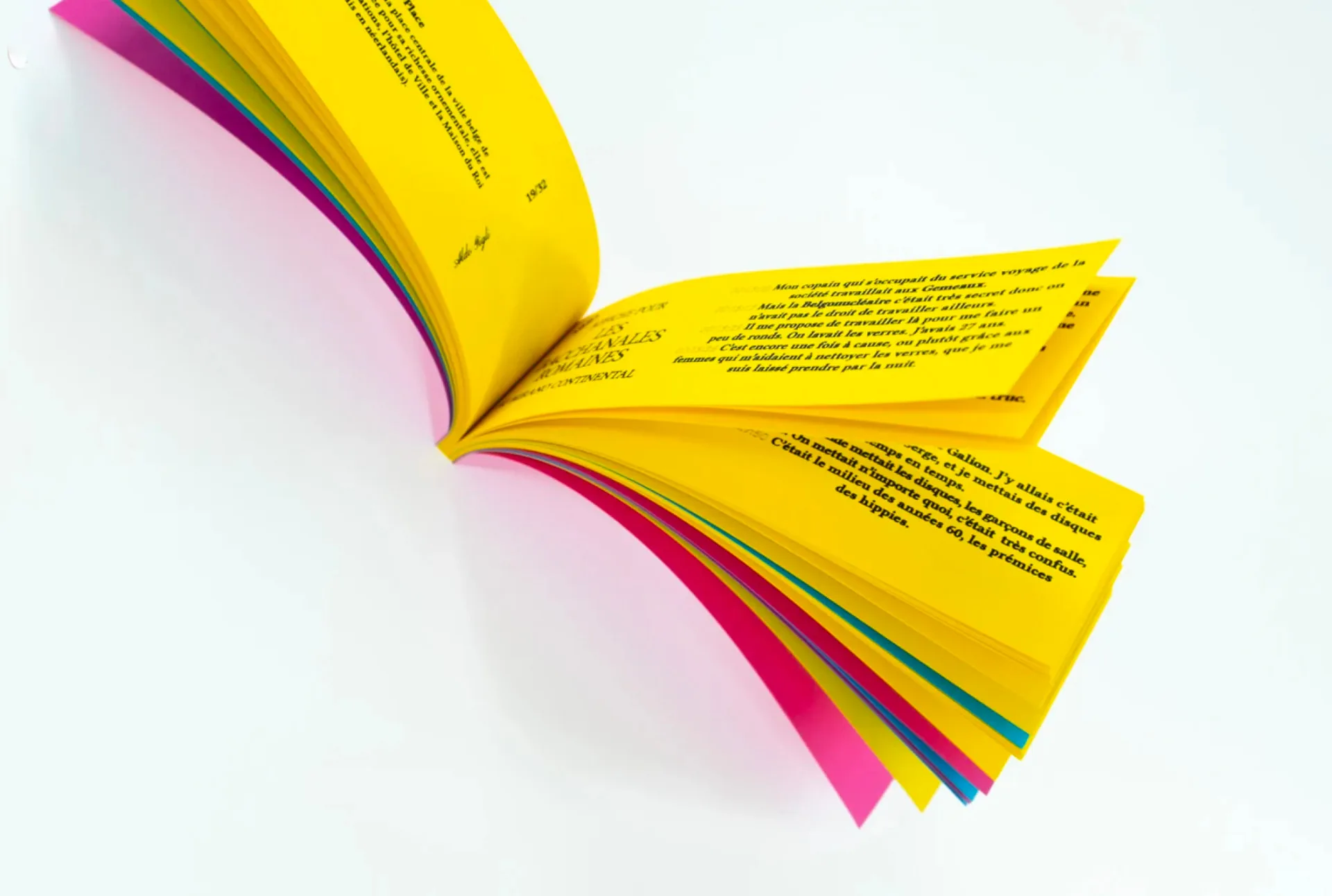 Photographié en plein élan, le carnet prend la pose comme une arche : pages jaunes en porte-à-faux, tranches rose, turquoise et vert. Un objet de papier qui a gardé le sens du spectacle de son sujet.