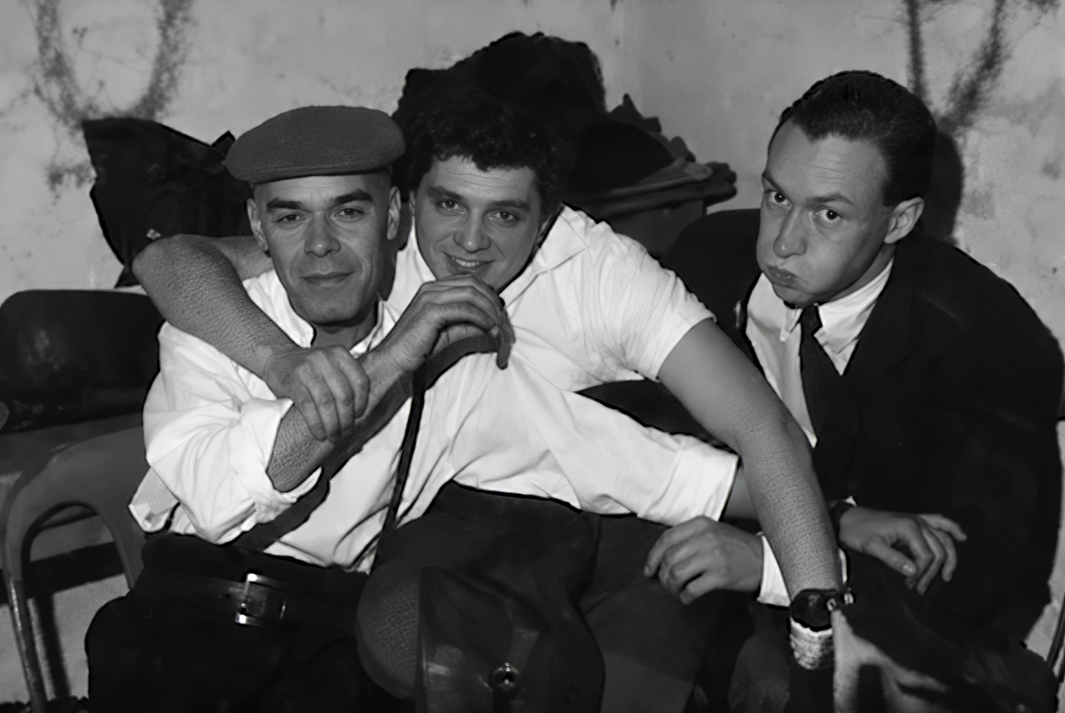 Photographie noir et blanc, format horizontal. Trois amis sont assis côte à côte au Mirano Continental, dans une pose décontractée qui tranche avec le costume-cravate.