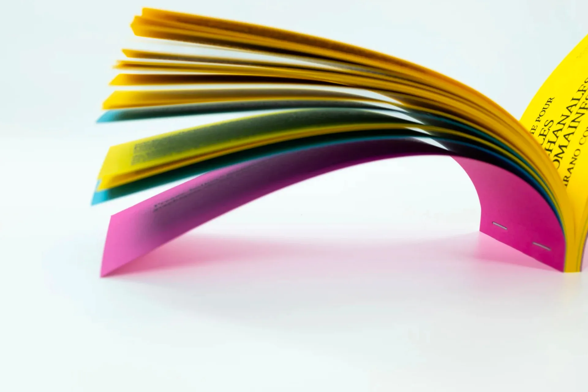 Vu de la tranche, le carnet se lit comme une palette d'affiches superposées : jaune, turquoise, magenta, assemblés à l'agrafe. La couleur comme sommaire, la nuit comme programme.