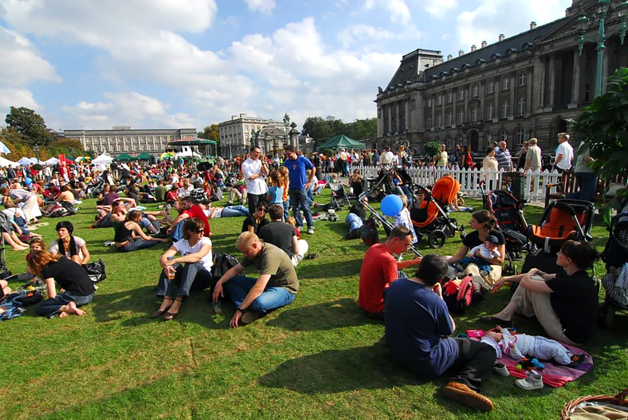 Familles et groupes d'amis installés dans l'herbe, entre les stands et le Palais royal.
