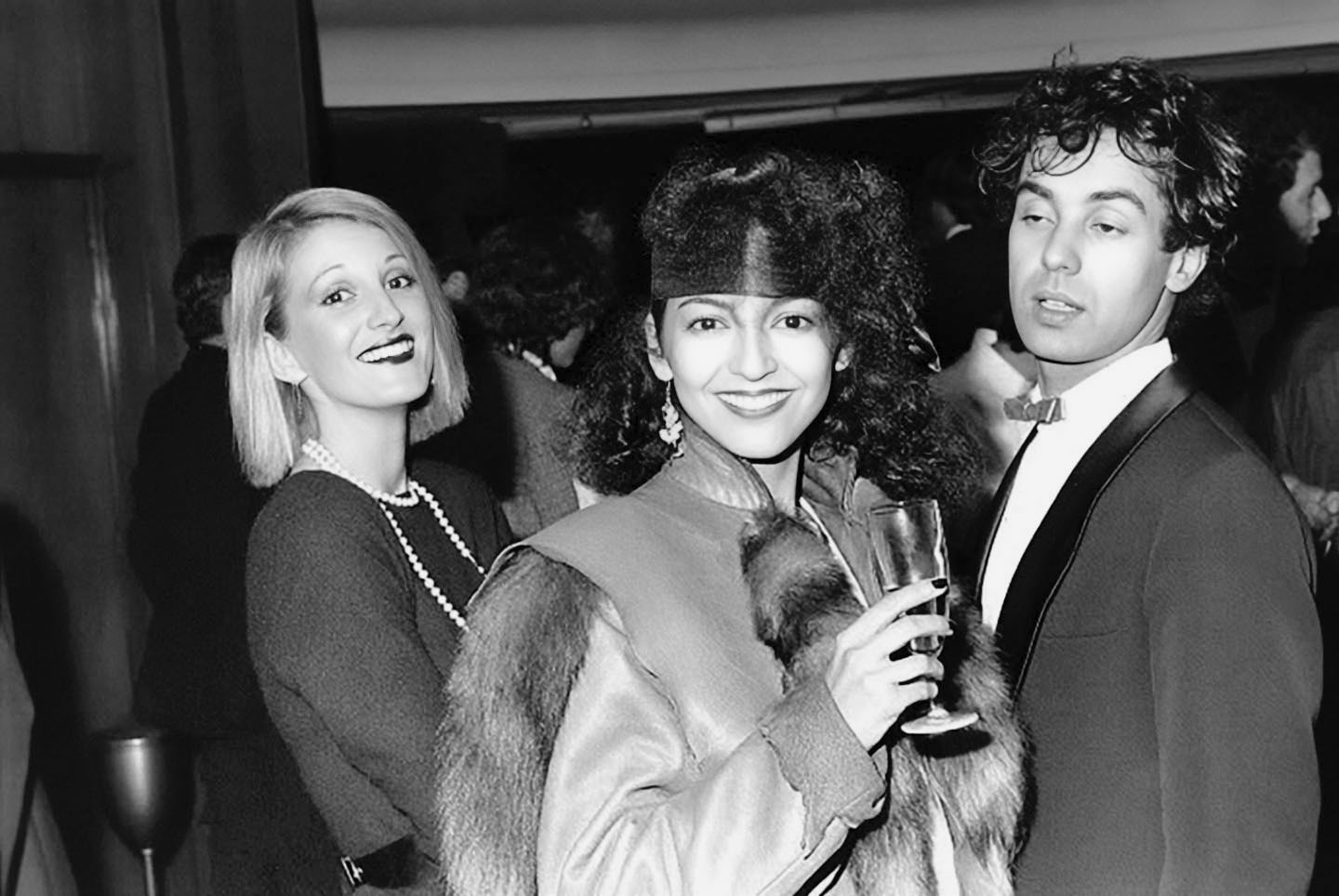 Photographie noir et blanc, format horizontal. Trois clients du Mirano Continental posent côte à côte, souriants, dans l'ambiance feutrée des nuits du club.