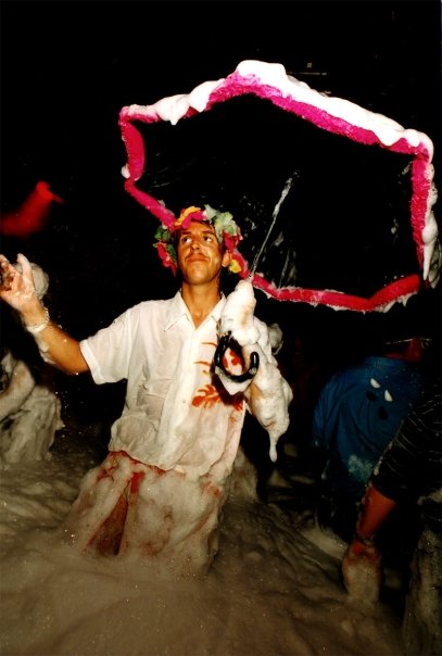 Bubu, a flower crown on his head, umbrella open in the foam.