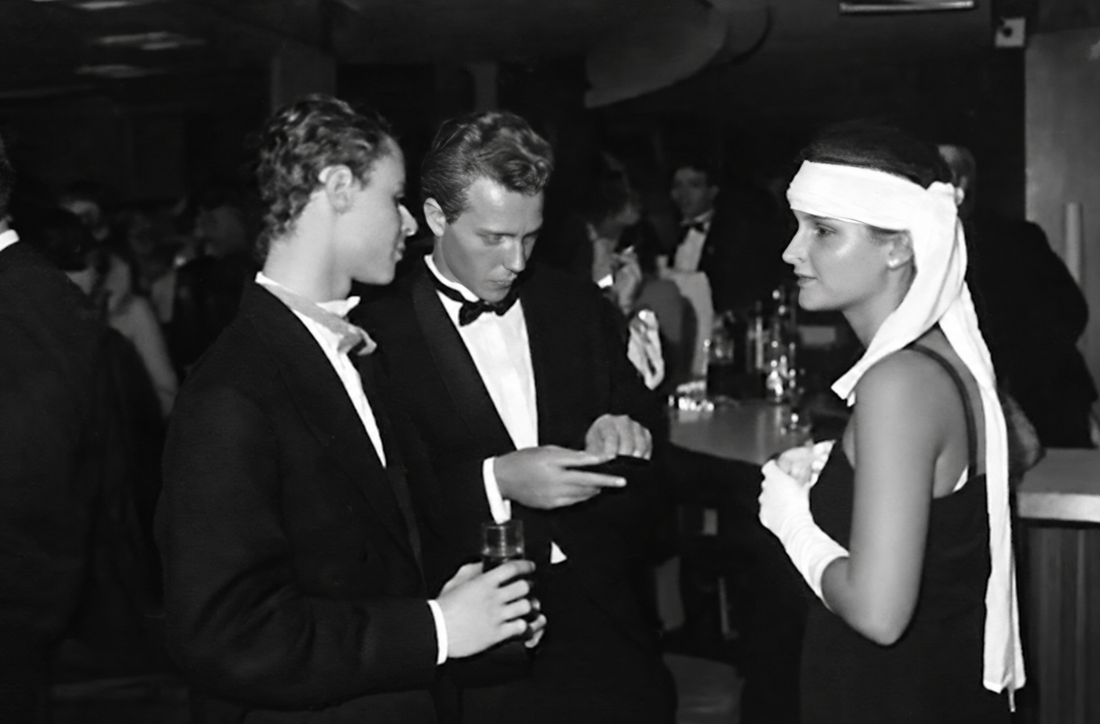 Photographie noir et blanc, format horizontal. Au bar du Mirano Continental, une femme portant un bandeau blanc discute avec un homme en smoking, tandis que d'autres clients s'attardent en arrière-plan.